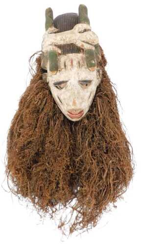 A Dan African tribal mask, decorated with green serpents, etc., and with raffia fringing, the...