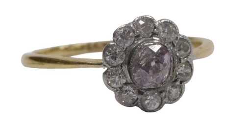 A pink diamond centred flowerhead ring, in a surround of rose cut white diamonds, in yellow...