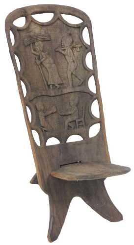 An African Mpingo birthing chair, the back carved with figures, with a detachable spoon shaped...