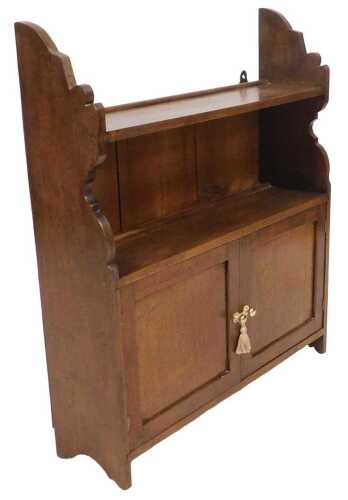 A late 19th/early 20thC oak wall shelf, with two shelves, shaped sides, and two panelled doors,...