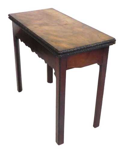 A George III mahogany tea table, the rectangular top with a carved border enclosing a polished...