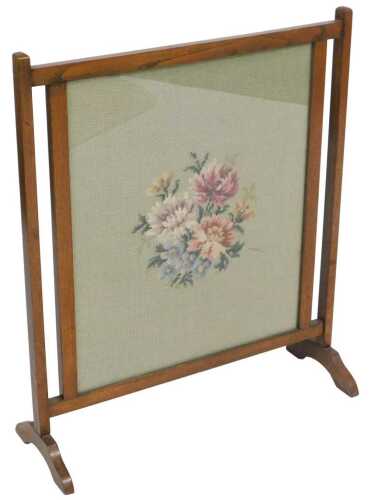 An Edwardian mahogany fire screen, inset with a floral woolwork panel, 65cm high, 56cm wide.