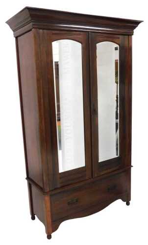 An Edwardian walnut wardrobe, with a moulded cornice above two mirrored doors and a drawer, on...