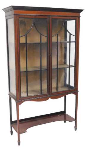 An Edwardian mahogany and boxwood strung display cabinet, the top with a moulded cornice above...