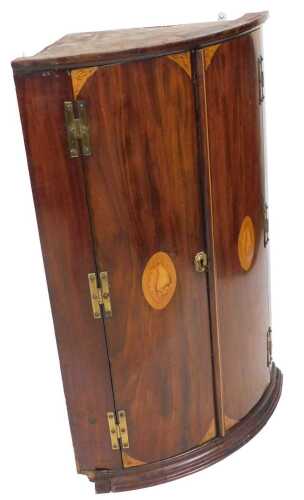 A George III mahogany bow front hanging corner cupboard, the outswept pediment above a pair of...