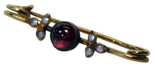 An Edwardian bar brooch, centred with a red cabochon stone, and flanked by two seed pearl set...