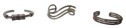 Three silver torc bangles, comprising one of waved design, the other with baton markers, and an...
