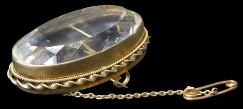 A 20thC brooch, the oval faceted rock crystal in a Pinchbeck rubover frame, with double...