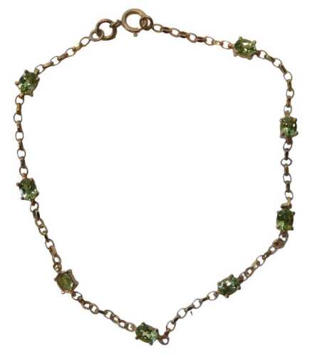 A 9ct gold peridot bracelet, set with eight oval cut peridots, each in a basket setting, on a...