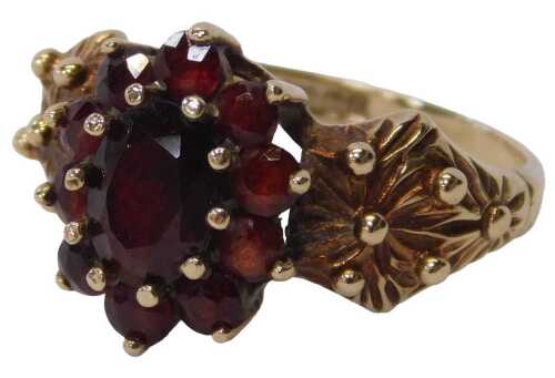 A 9ct gold floral cluster ring, set with an arrangement of garnets, with a large centre stone...