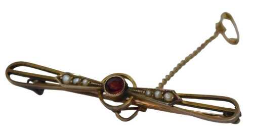 A 20thC bar brooch, the central circular design set with a rubover garnet, and six seed pearls,...