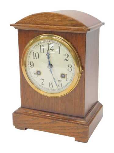 An early 20thC oak cased mantel clock, the circular cream dial bearing Arabic numerals, with an...
