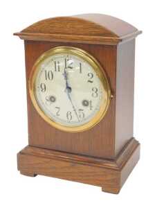 An early 20thC oak cased mantel clock, the circular cream dial bearing Arabic numerals, with an...