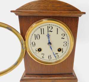 An early 20thC oak cased mantel clock, the circular cream dial bearing Arabic numerals, with an... - 2