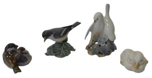 A group of Royal Copenhagen porcelain birds, to include two white doves perched on a floral...