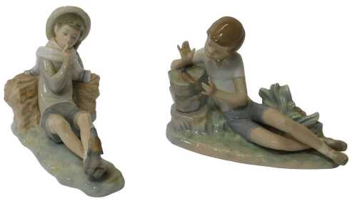 Two Lladro porcelain figures, each modelled as a boy, one beside a bird, and the other wearing a...