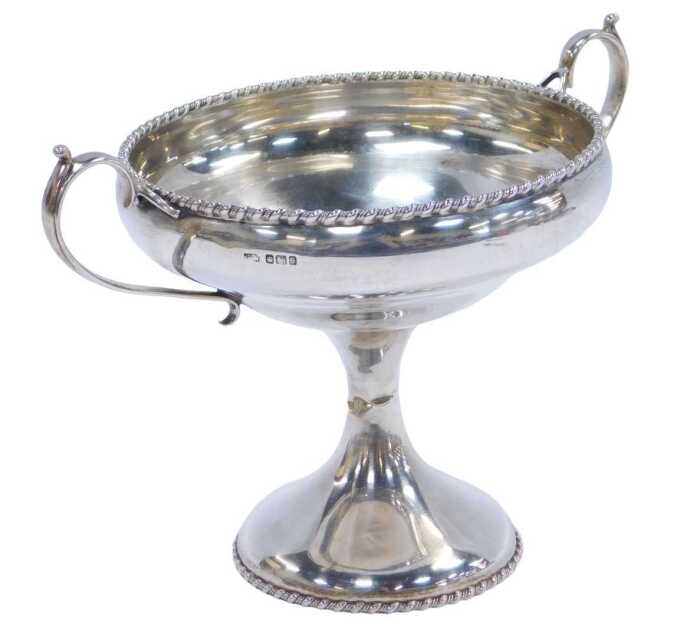 A George V silver twin-handled tazza, with a gadrooned rim, raised on an hourglass stem, on a...
