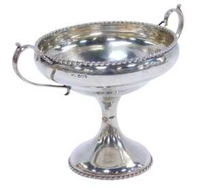 A George V silver twin-handled tazza, with a gadrooned rim, raised on an hourglass stem, on a...
