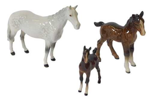 A Beswick pottery figure of a dapple grey horse, 17cm high, together with two bay foals, 16cm...
