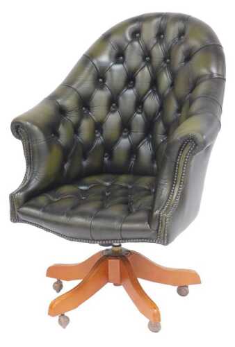 A buttonback Chesterfield-type office chair, upholstered in green leather, on an X-shaped base...