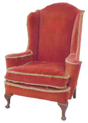 A mahogany wingback chair, in the George III style, upholstered in red velvet with gold fringing,...