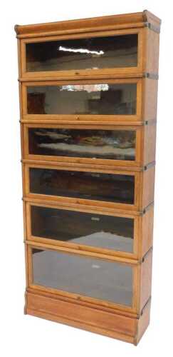 A Globe Wernicke oak six-section bookcase, with three sliding glazed doors, on a plinth, bearing...