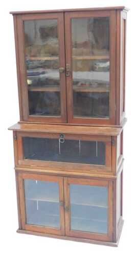 An early 20thC teak sectional bookcase, the top with two glazed doors, the base with a fall...