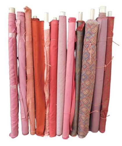 Various bolts of upholstery fabric, differing designs, predominantly red and pink. (a quantity)