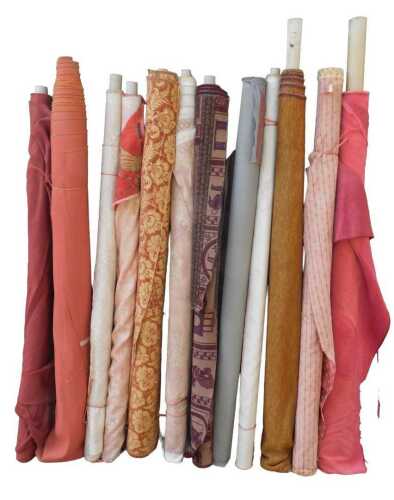 Various bolts of upholstery fabric, differing designs, predominantly reds. (a quantity)
