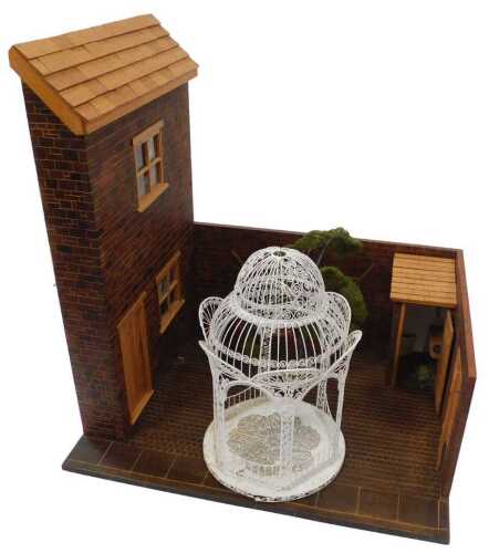 A terraced house frontage and terraced garden, with planters, tree, and wirework gazebo.