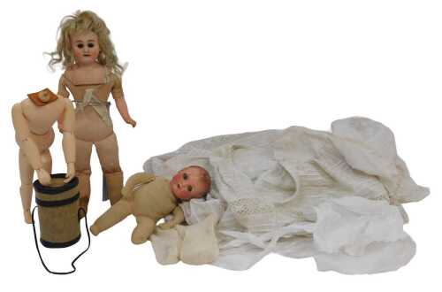 A small bisque headed doll, numbered 3093, on stand, with clothing, a small articulated doll...