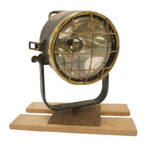 A brass ship's spotlight, mounted on a wooden plinth.