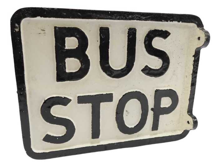 A reproduction cast bus stop sign, black lettering on a white background.
