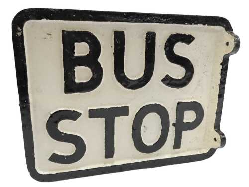 A reproduction cast bus stop sign, black lettering on a white background.