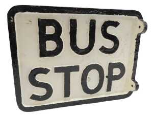 A reproduction cast bus stop sign, black lettering on a white background.