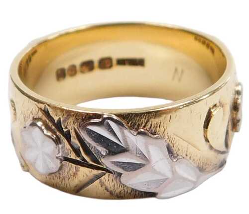 An 18ct bicolour gold wedding band, with raised flower and foliate decoration, size N, 8.5g.