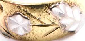 An 18ct bicolour gold wedding band, with raised flower and foliate decoration, size N, 8.5g. - 2