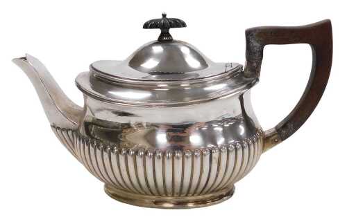 An Edward VII silver teapot, of semi fluted form, with ebonised handle, Birmingham 1902, 17.06oz...