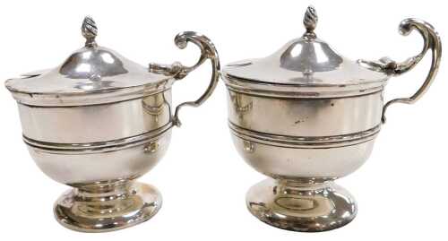 A pair of Edward VII silver mustard pots, with Bristol blue glass liners, with a scroll handle...
