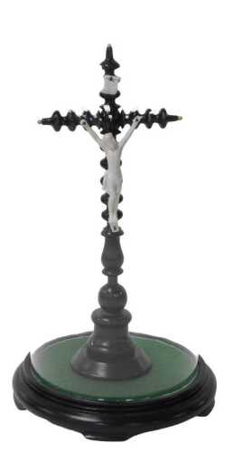 A late 19thC French ebonised wood and ceramic crucifix, on a black socle, with a glass dome,...