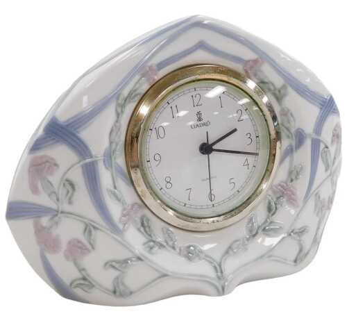 A Lladro porcelain cased clock, moulded with trailing flowers and leaves, circular white dial...