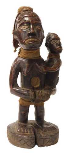 A Congolese tribal figure of a female holding a child, with cloth hat, on oval base, 41cm high.