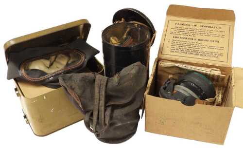 Four World War II period gas masks, including two with tin cases.