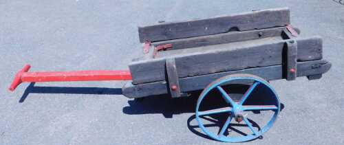 A wooden pull along cart, with painted cast iron wheels, 116cm x 60cm.