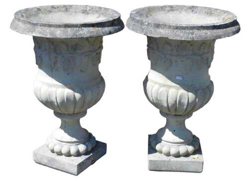 A pair of composition stone campana style garden urns, each decorated with a band of grapes and...