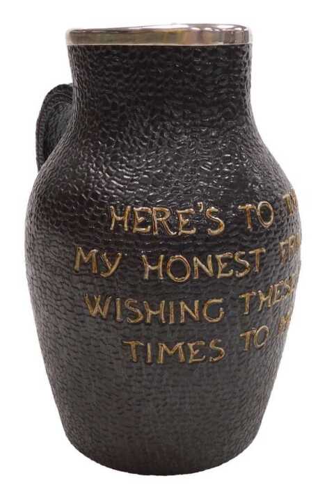 A Doulton Lambeth stoneware leather jug, with a silver mount, to tube line decorated "Here's to...