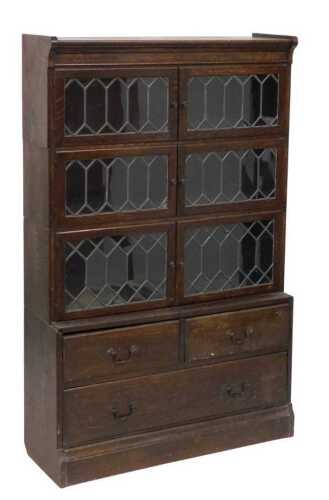 An early 20thC oak sectional bookcase, the top formed in three sections with leaded glass doors,...