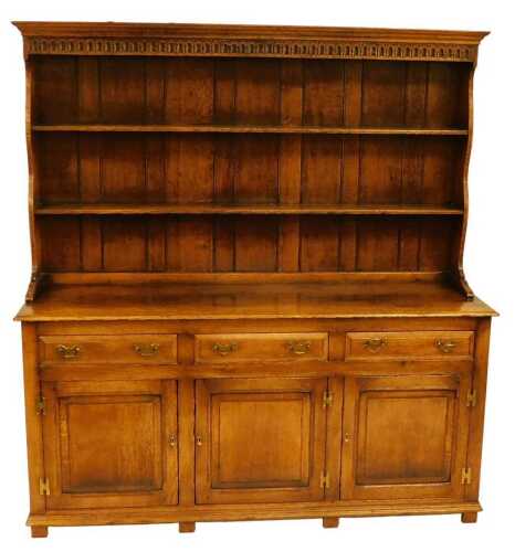 A 20thC oak dresser, the top with a moulded cornice above a carved frieze, above a two shelved...