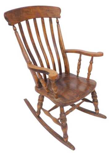 A 19thC elm and beech lath back grandfather rocking chair, with a solid seat and turned legs...