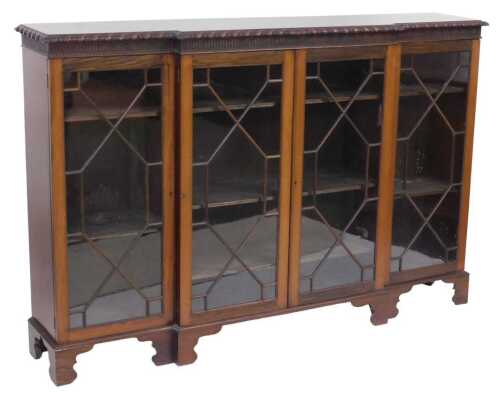 A late Victorian mahogany breakfront bookcase, with a leaf moulded border above four astragal...